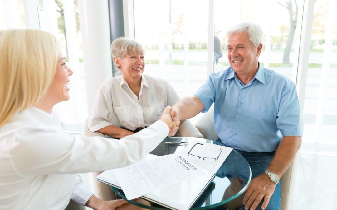 Happy senior couple shaking hands with woman insurance agent