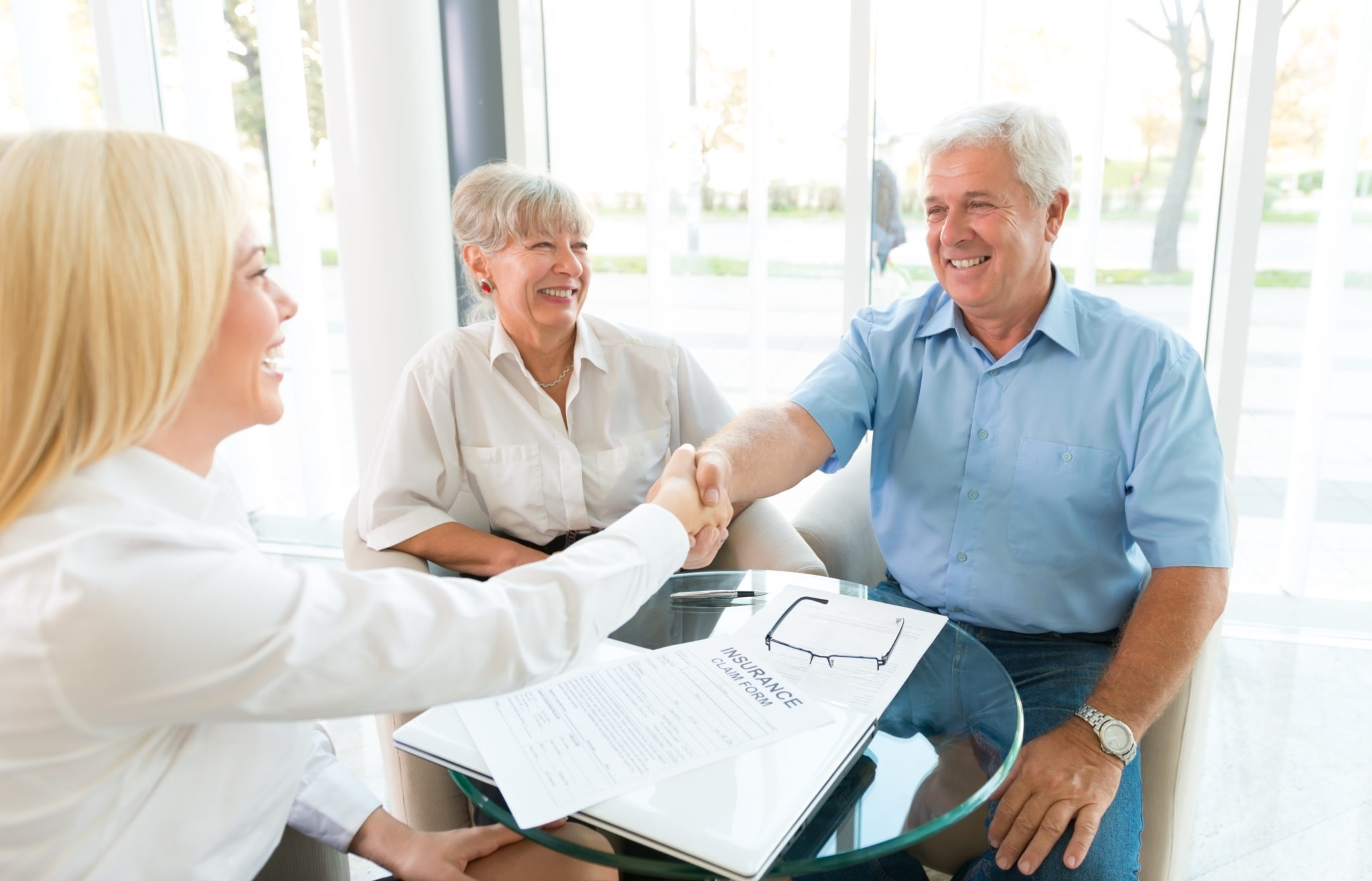 Happy senior couple shaking hands with woman insurance agent