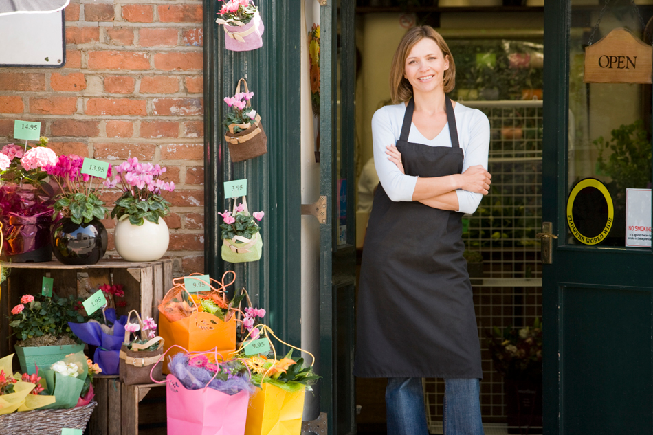 Woman standing at the front of a flower shop.